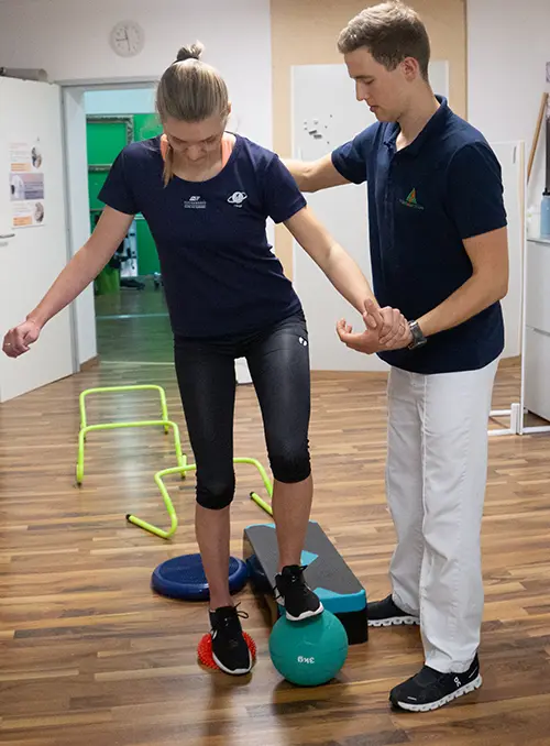 Therapeutin unterstützt Patient beim Balancetraining